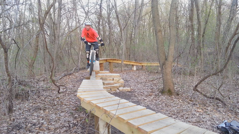 Raised bridge skinny in the optional X section; the rock steps to the left of my front wheel provide an optional easier exit; west loop, Carver Lake MTB trail