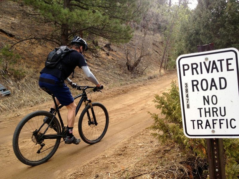 This terribly misleading sign means you're in the right place.  This road is absolutely open to public hiking and biking.  Rural Boulder County roads are full of these misleading signs that should be taken down.  The land around the road is public, you have every right to be on the road!