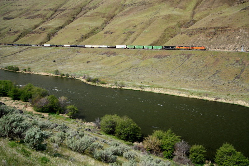 A long freight train snakes its way along the west bank of the river.