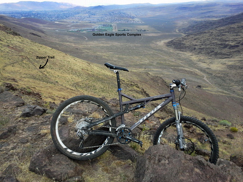 The view north from the bluffs at the top of the Zipper. You can see the Zipper trail switchbacking down the slope behind and Golden Eagle Sports Complex in the background. Just right of the handlebars in the photo is Graffiti Rock.