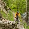 Narrow singletrack flanked one one side by stone walls and the other by Crescent Creek