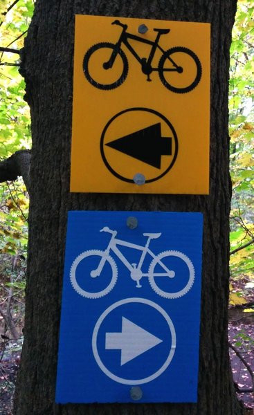 Example of yellow and blue corrugated plastic signs used to mark River Bends Park trails.