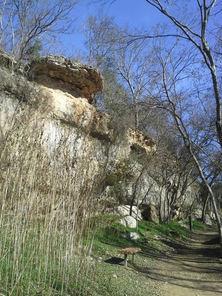 Scenic overhanging rocks and park benches along the pack gravel section of North San Gabriel River Trail