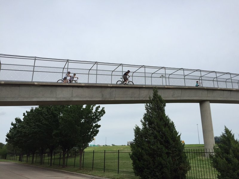 Friends riding over the pedestrian bridge over Kellogg