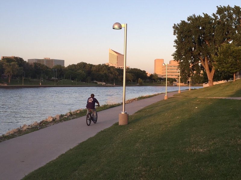 West side of the downtown river path, across from the Keeper of the Plains