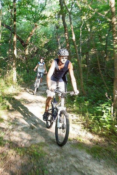 Bikers ride along a wooded section of the Cowboy Trail. (Photo by Nebraska Game and Parks with permission by Kirk Nelson, Assistant Division Administrator.)