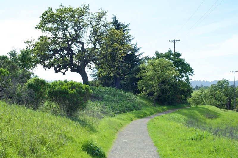 The trail is gravel at this point as it hugs the hill. The golf course is off on the left.