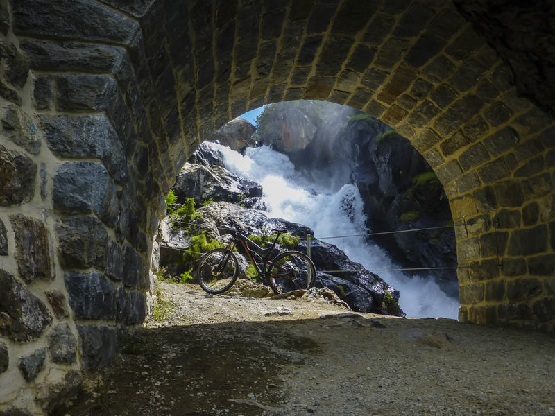 Bernina Creek spills over a waterfall viewed through one of the bridges of the Bernina Express along the mountain bike route.