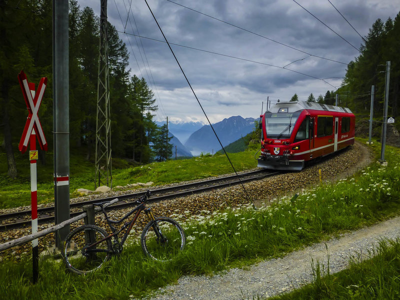 The mountain bike route crosses the Bernina Express tracks several times as it descends from the pass into Poschiavo.