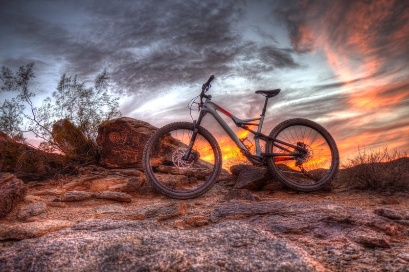 A brilliant sunset behind petroglyph rocks.