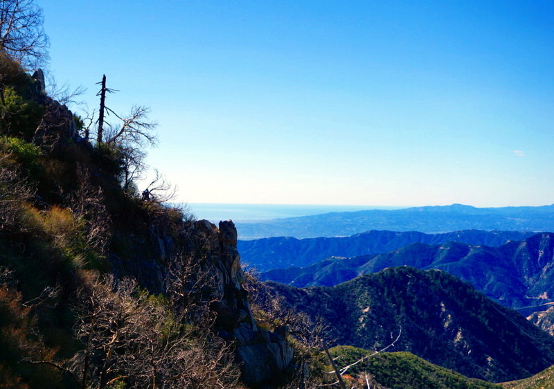 A faintly visible Carter, ignores the fantastic views as he rounds the corner into the Strawberry Peak Trail's downhill section. In the distance is the Lukens, Verdugos, and Santa Monica Mountain ranges.