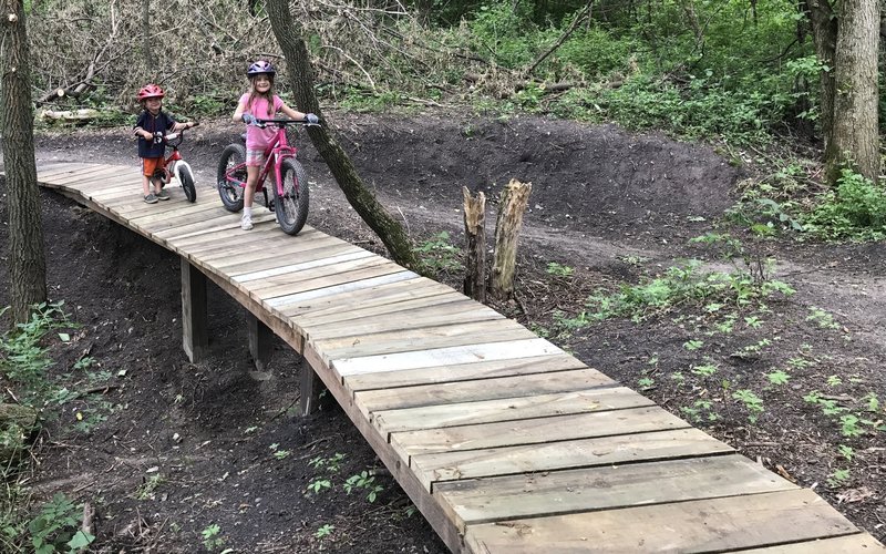 Riding a wide bridge over a ravine on a green trail at Bertram!