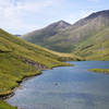 Biking past the lake at the top of Devil's Pass while another group goes for a swim.