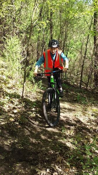 Riding a wooded section of rolling trail traversing a steep slope.