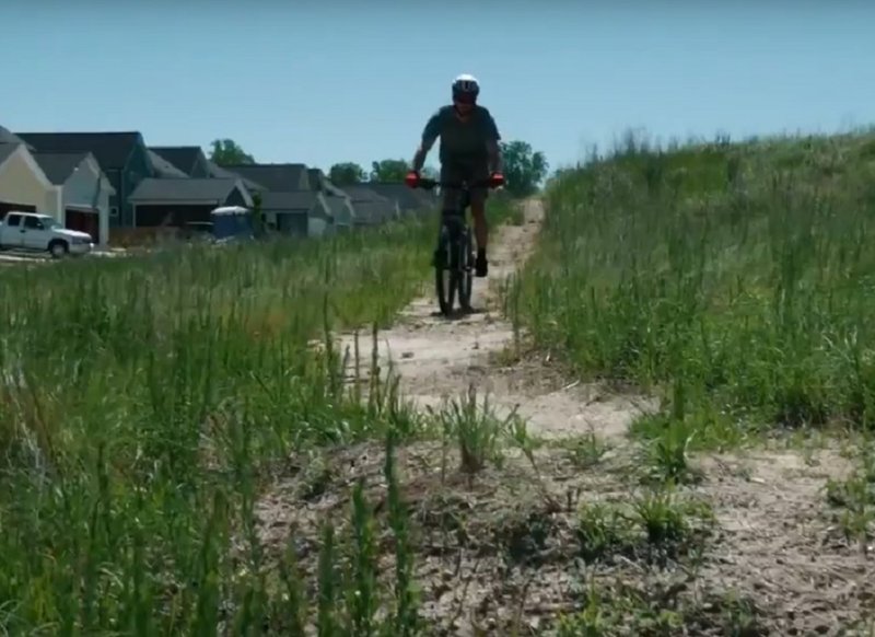 Rider on trail crossing a grassy hillside.