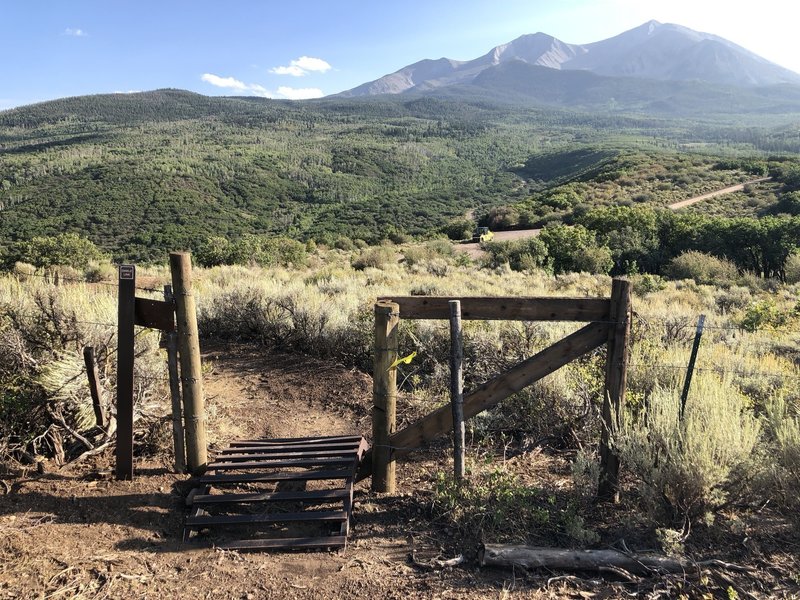 Ride over cattle guard at fence line near parking area on Dinkle Link.  View of Mount Sopris and Hay Park area beyond.