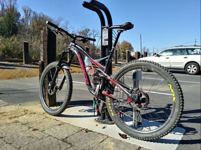 Bike stand at trailhead parking lot with air pump and various tools.