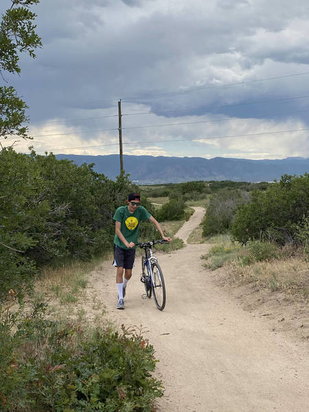 Josh walking his bike up an easy uphill after a long day's work.