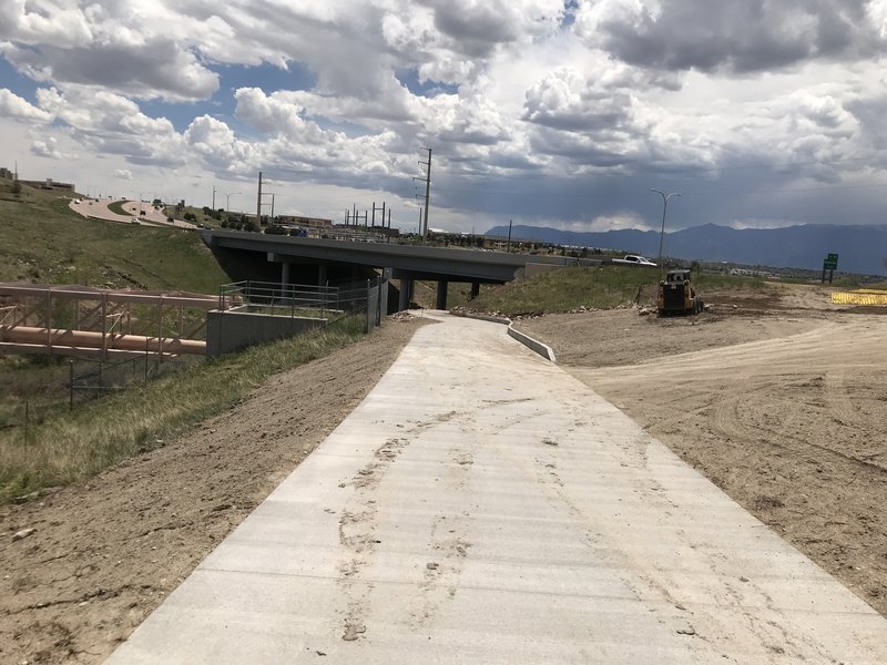 The trail has been paved east from Frank Castello Park under Powers Blvd and north past the pipeline. This photo is looking south from the end of the pavement. The bridge on Powers Blvd over Cottonwood Creek is in the center.