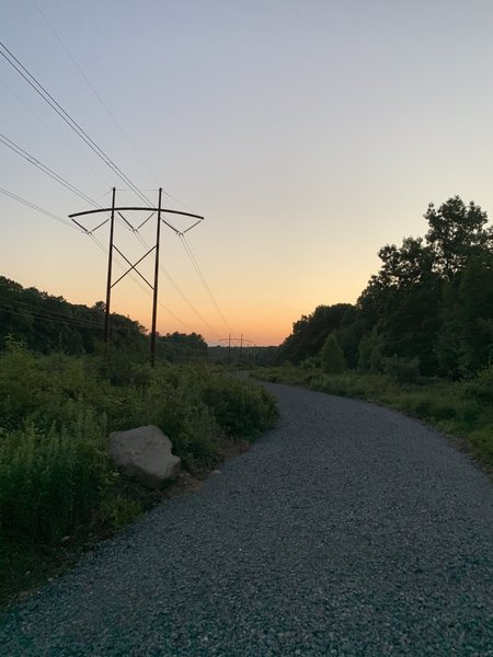 Sunsetting over gravel road with power lines in the background.