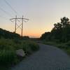 Sunsetting over gravel road with power lines in the background.