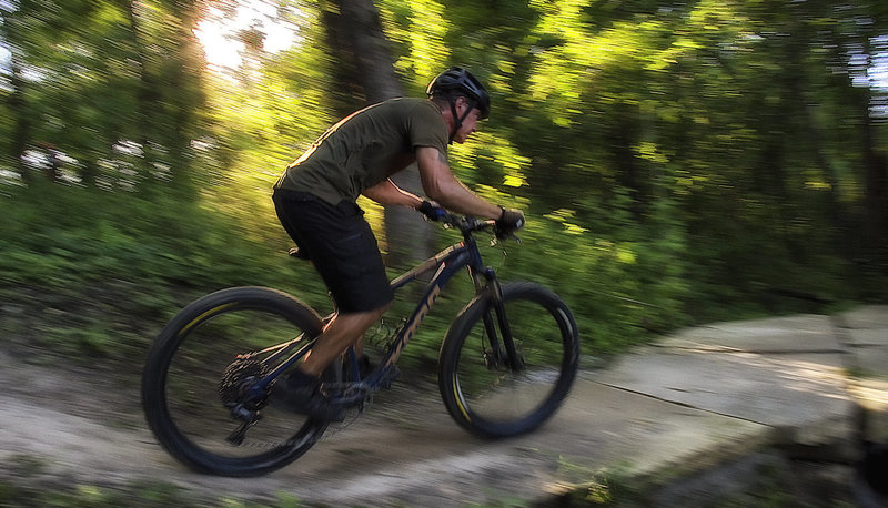 Rider crossing rock bridge on the lower portion of the Creekside flow trail.