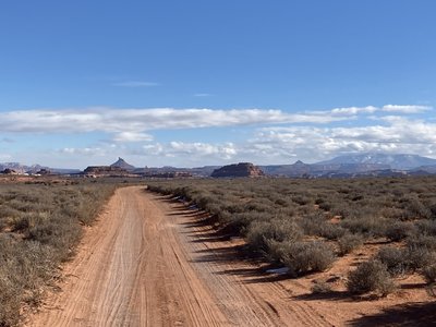 Heading back to the trailhead through a sandy bit. Abajos and Six Shooter Peaks in distance.