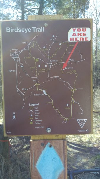 A trail marker with a map near the cemetery.