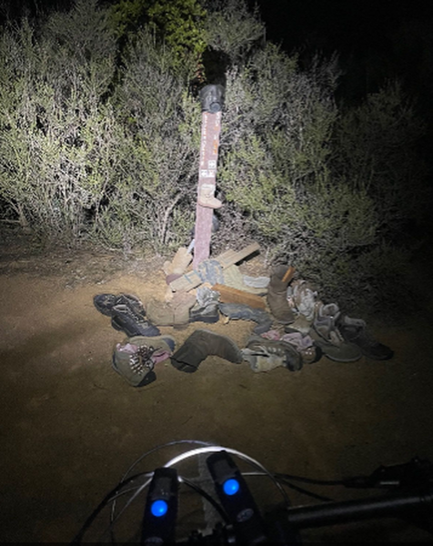 Pile of boots at the trail marker at night.