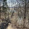 View above the river, across the pond and to the farm from the river overlook on the wooded singletrack
