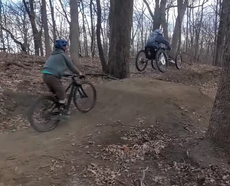 An adaptive mountain bike rider enjoying the air with his follower on Space Jam.