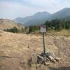 Trail restriction sign as route starts east. Trail braids its way downslope to stock tank.