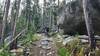 Riding past a massive granite boulder showing typical rocky terrain of the Nez Perce Trail.