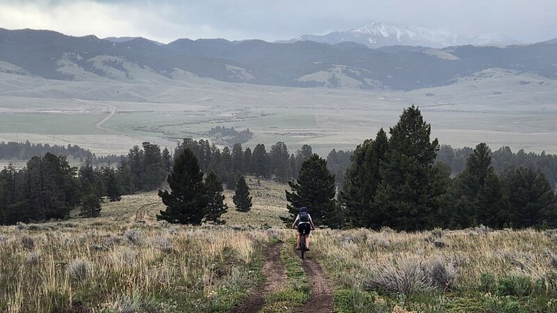 A rider descends Divide Creek Ridge with the Highland Mountains in the background.