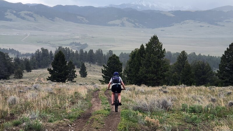 A rider descends Divide Creek Ridge with the Highland Mountains in the background.