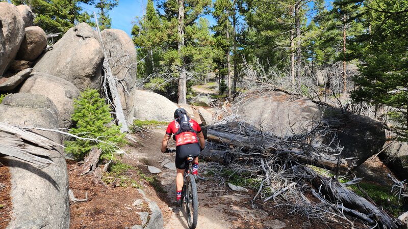 A mountain bike rider navigates between large granite boulders on the Continental Divide Trail.