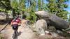 A mountain bike rider rides past a large granite boulder on the Continental Divide Trail.