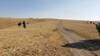 A large open meadow, and one of the places where the CDT trail crosses a dirt road. A marker post is shown where the CDT traverses to the left of the road.