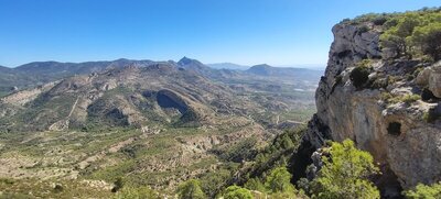 Exposed path on the Sit mountain, with the Maigmó peak in front and the Mediterranean Sea in the background.