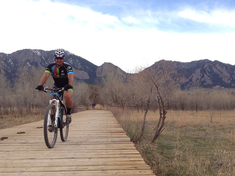 Crossing the bridge on South Boulder Trail with the Flatirons in the background.